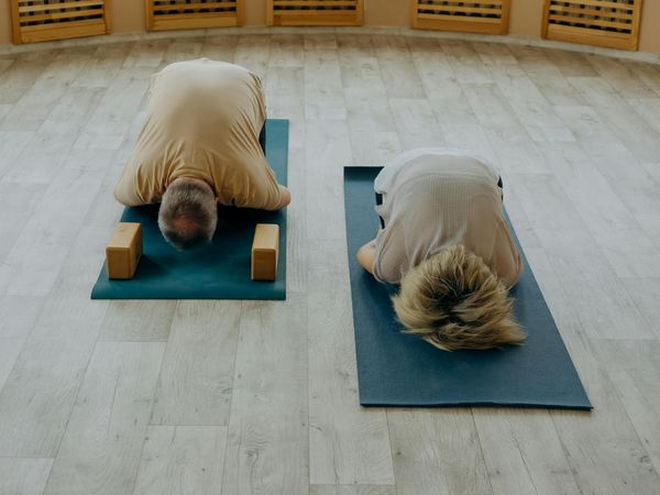 Group of people in a bright studio practicing gentle yoga stretches.